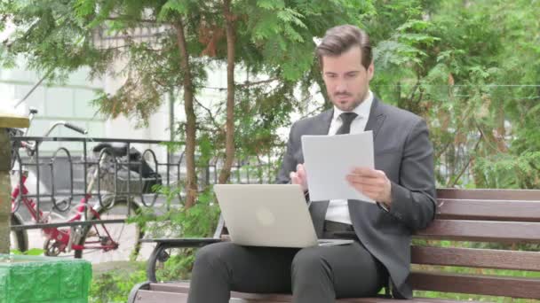 Средневековый бизнесмен празднует во время работы над ноутбуком и документами на открытом воздухе - Кадры, видео