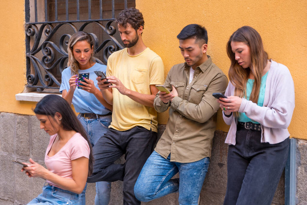Group of multiracial friends looking serious at the phone in the city, concept of youth hooked on mobile - Φωτογραφία, εικόνα