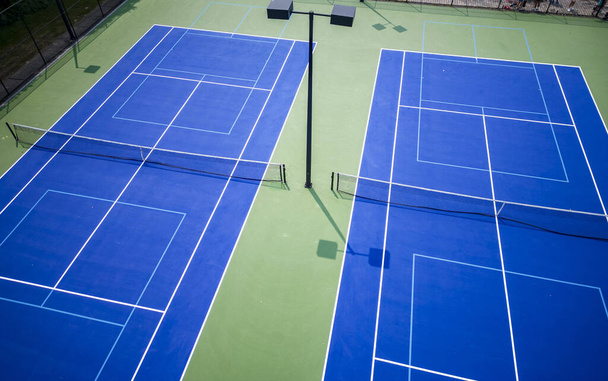 Vue de drone de deux courts de tennis qui ont également des lignes de pickleball et des lumières pour jouer la nuit. - Photo, image