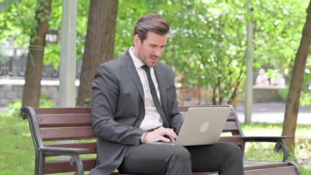 Молодий бізнесмен шокований втратами на ноутбуці на відкритому повітрі - Кадри, відео