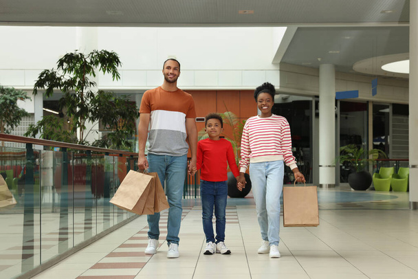 Family shopping. Happy parents and son with purchases in mall - Фото, изображение