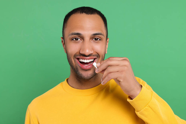 Portrait of happy man with bubble gum on green background - Фото, зображення