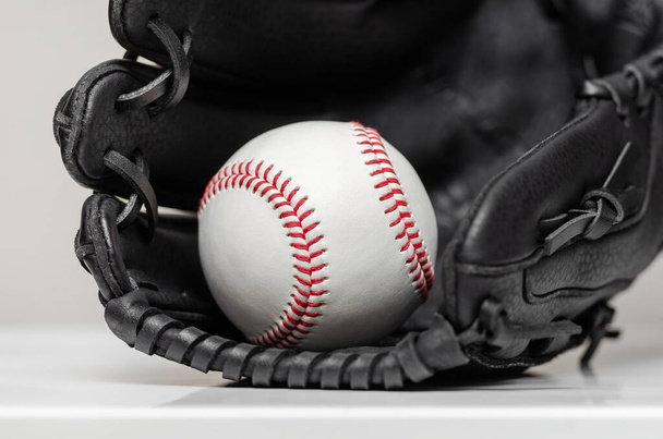 Close-up van een witte honkbal bal met rode steken in honkbal handschoen - Foto, afbeelding