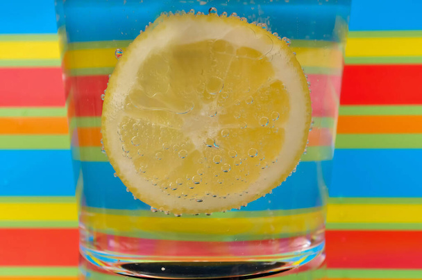 Lemoniada napój gazowany w przezroczystej szklance z kolorowym tłem pokazującym musujące bąbelki dobre dla multimedialnego tworzenia tła - Zdjęcie, obraz