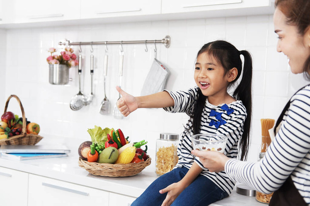 リトルアジアの少女の子供は,休日に自宅でキッチンで母とタイのデザートを食べています. 家族の暖かさと赤ちゃんの成長コンセプト - 写真・画像