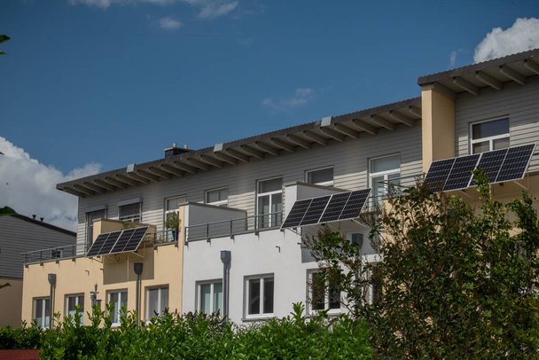 A terraced house with solar power plant on a balconies to generate green electrical energy for home. Balcony solar power station eco-friendly to use renewable energy.  - Photo, Image