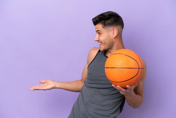 jong Kaukasische vrouw basketbal speler man geïsoleerd op paarse achtergrond met verrassing uitdrukking terwijl op zoek kant - Foto, afbeelding