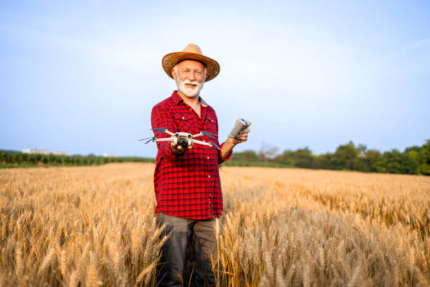 Фермер, использующий беспилотные технологии в поле для распыления и мониторинга культур. - Фото, изображение