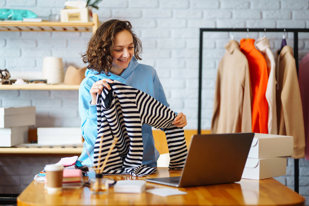 Clothing store: young happy woman, small business owner, seller using tablet checks and packs orders of online store, e-commerce. Online sales. - Photo, Image