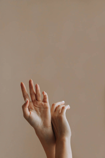 tender hands of the girl are raised up on a plain background. Vertical photo - Foto, imagen