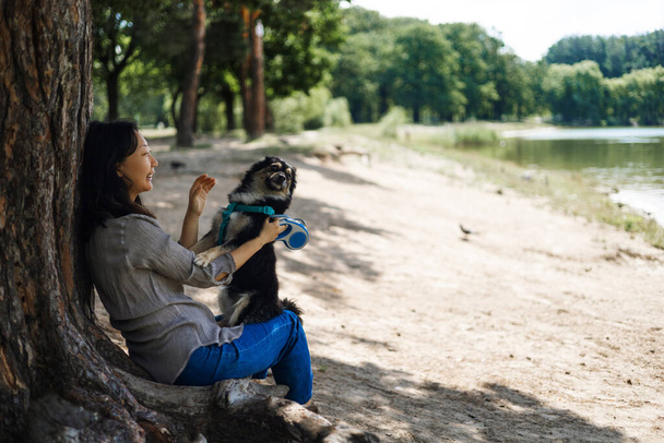 Junge Asiatin mit Hund bei einem Waldspaziergang. Ein Mädchen geht mit einem Hund im Park spazieren. - Foto, Bild