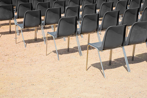 Kültéri mozi fekete műanyag székek egy sorban a kavicsos padló - Fotó, kép
