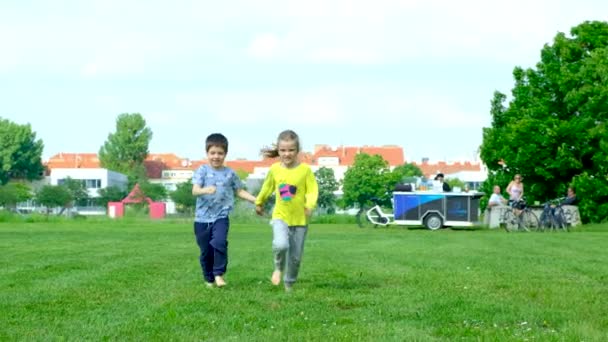 Un ragazzino e una ragazza corrono scalzi sull'erba. Il concetto di amicizia per bambini e infanzia felice. - Filmati, video