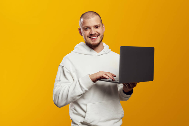 Onnistunut valkoihoinen nuori mies opiskelija freelancer kannettavan tietokoneen, katselu webinars, työskentelevät etänä, e-oppimisen verkossa eristetty keltaisella taustalla - Valokuva, kuva