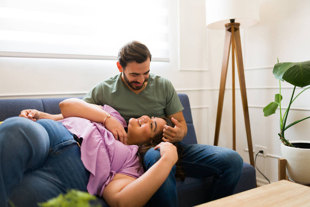 Houkutteleva mies, jolla on romanttinen hetki onnellisen tyttöystävänsä kanssa rentoutuen yhdessä ja nauraen sohvalla - Valokuva, kuva