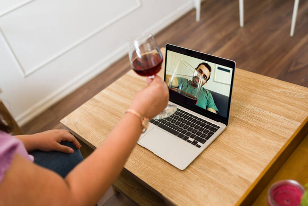 Ζευγάρι μεγάλων αποστάσεων που έχουν μια εικονική ημερομηνία και πίνουν κρασί μαζί, ενώ σε μια online βιντεοκλήση στο φορητό υπολογιστή - Φωτογραφία, εικόνα