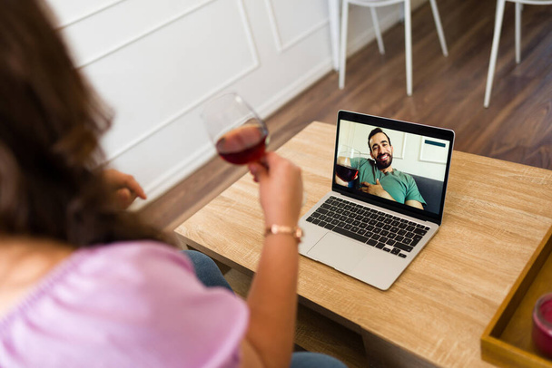 Ευτυχισμένο ζευγάρι που έχουν μια εικονική ημερομηνία και σε απευθείας σύνδεση βιντεοκλήση στο laptop, ενώ απολαμβάνοντας το κρασί και μιλώντας για τη σχέση τους - Φωτογραφία, εικόνα