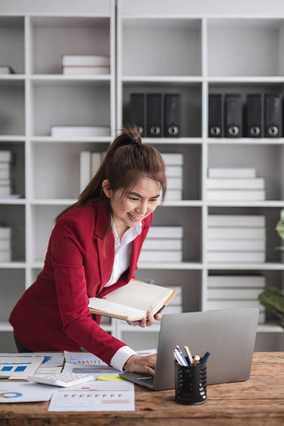 Mooie Aziatische zakenvrouw vieren tijdens het gebruik van laptop op kantoor en tonen vreugde. Startup klein bedrijf en succesvol concept. - Foto, afbeelding