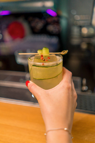 Cliente che tiene delizioso cocktail di gin garden appena fatto con cetriolo nel concetto di bevande bar bar mano - Foto, immagini