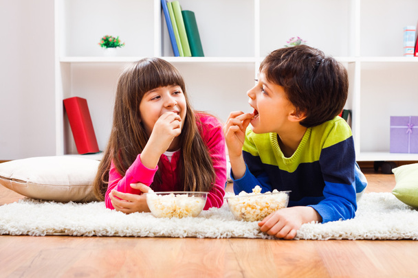 Little girl and little boy enjoy eating popcorn - Photo, Image