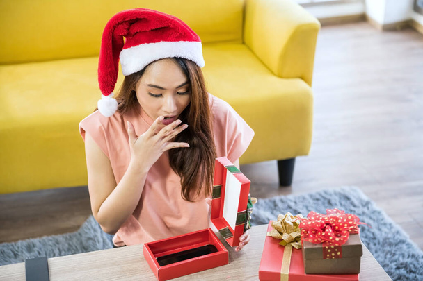Hermosa mujer asiática sorpresa para conseguir teléfono inteligente para regalo de Navidad en la caja actual. Sorprendido por su adorable novio o esposo. - Foto, imagen