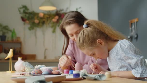 Pieni tyttö maalaus iloinen äiti tehdessään pääsiäisen koristeet kotona - Materiaali, video