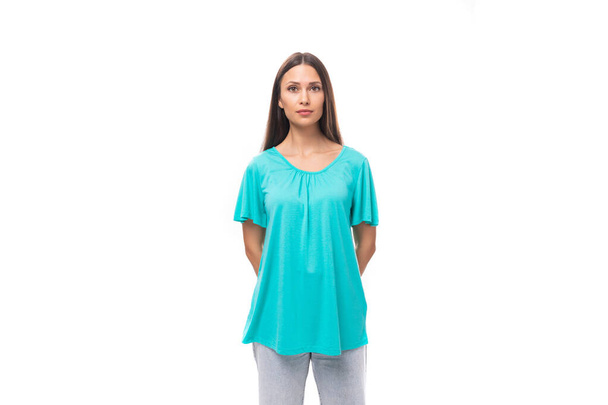 young european woman with dark long hair dressed in a blue loose-fitting t-shirt on a white background with copy space. - Photo, Image