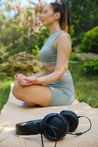 Dívka medituje a odkládá sluchátka. Selektivní zaměření na sluchátka - Fotografie, Obrázek