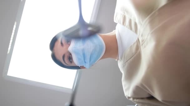 Вид сверху на женщину-стоматолога во время работы в стоматологическом кабинете. Стоматолог в маске во время стоматологического лечения инструментами. Своевременное лечение зубов - Кадры, видео