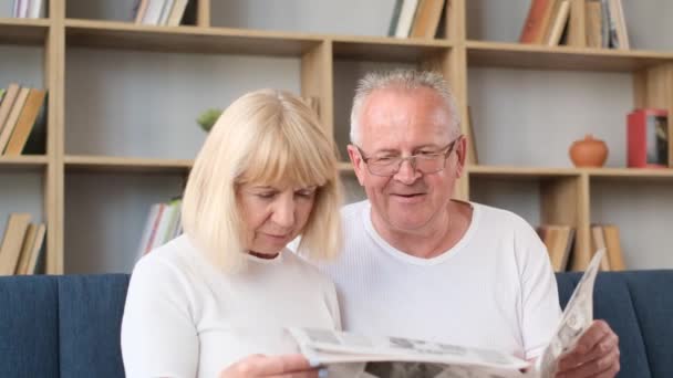 Włoscy emeryci siedzą w domu na kanapie i czytają najnowszą prasę. Szczęśliwa emerytowana para. Pionowe wideo - Materiał filmowy, wideo