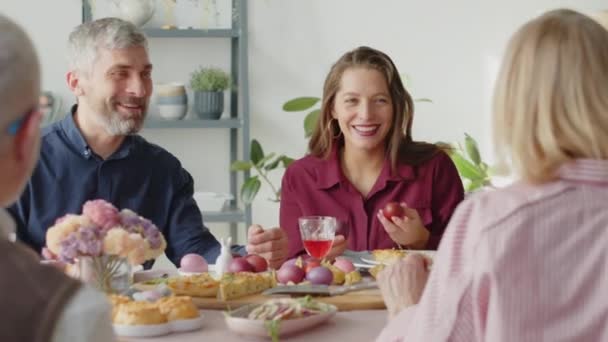 Über die Schulter eines fröhlichen Familienpaares, das beim Osteressen zu Hause mit den Großeltern plaudert - Filmmaterial, Video