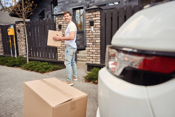 El hombre lleva cajas con cosas a la casa cuando se mueve - Foto, Imagen