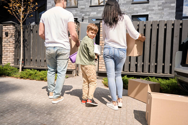 Família caucasiana carregando caixas para sua nova casa com sorrisos em seus rostos - Foto, Imagem