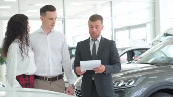 A lovely couple is talking to a manager while buying a car at a car dealership. Car dealership. - Felvétel, videó