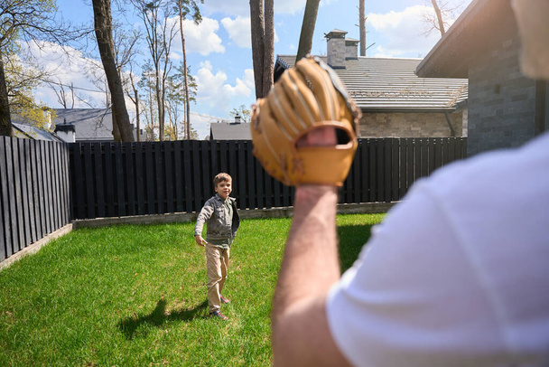 Biały mężczyzna w rękawiczce baseballowej bawi się z dzieckiem na jego terytorium. - Zdjęcie, obraz