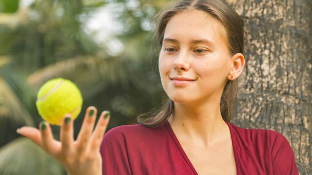 Eine junge Frau wirbelt einen Tennisball in der Hand. Hochwertiges Foto - Foto, Bild
