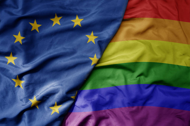 velká vlnící se realistická národní barevná vlajka Evropské unie a duhové homosexuální vlajky. makro - Fotografie, Obrázek