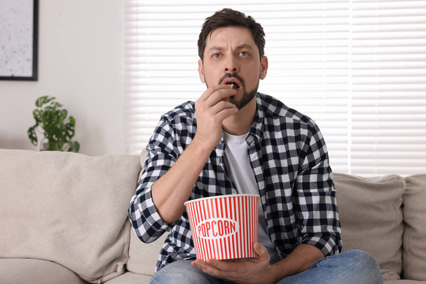 Man watching TV while eating popcorn on sofa at home - Φωτογραφία, εικόνα