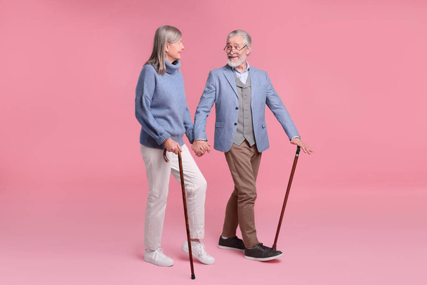 Senior man and woman with walking canes on pink background - Valokuva, kuva