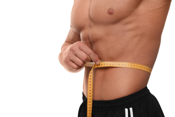 Athletic man measuring waist with tape on white background, closeup. Weight loss concept - Valokuva, kuva