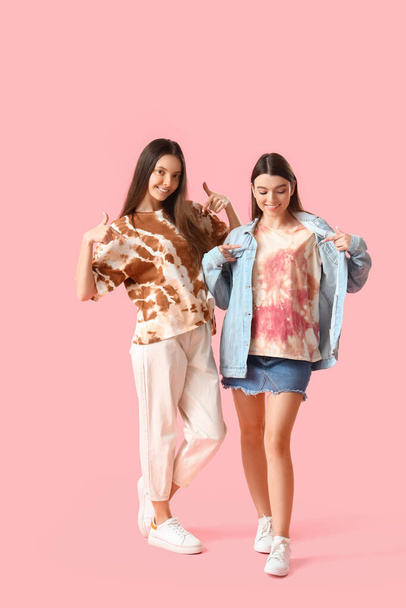 Stylish young women in tie-dye t-shirts on pink background - Foto, Imagen