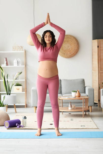 Sporty pregnant woman meditating at home - Foto, afbeelding