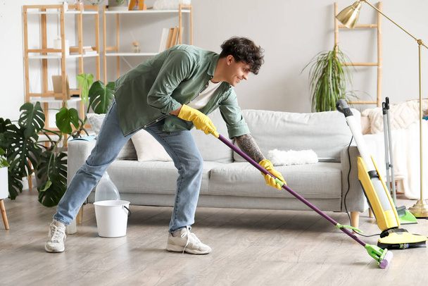 Young man mopping floor at home - Fotó, kép