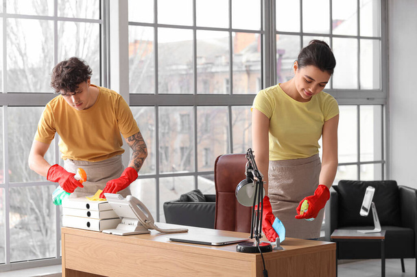 Junge Hausmeister putzen Arbeitsplatz im Büro - Foto, Bild