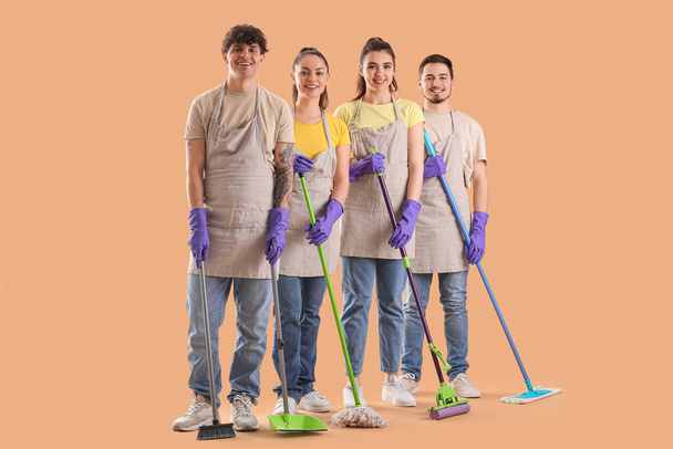 Nuoret talonmiehet siivoustarvikkeet beige tausta - Valokuva, kuva