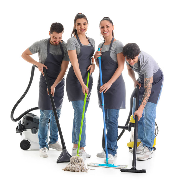 Young janitors with cleaning supplies on white background - Fotoğraf, Görsel