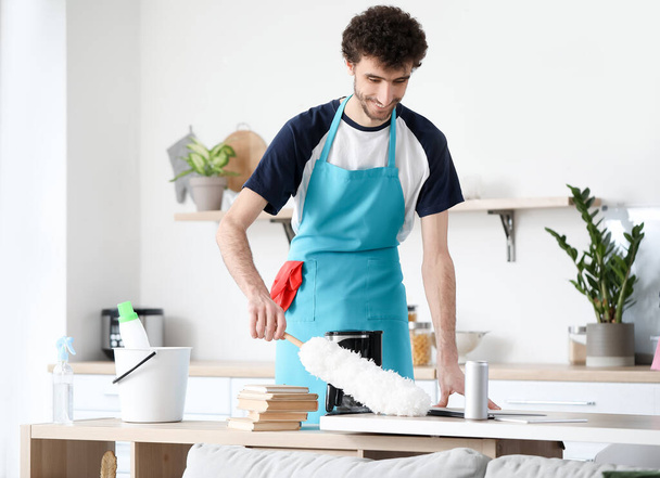 Jeune homme table de nettoyage avec pp-duster dans la cuisine - Photo, image