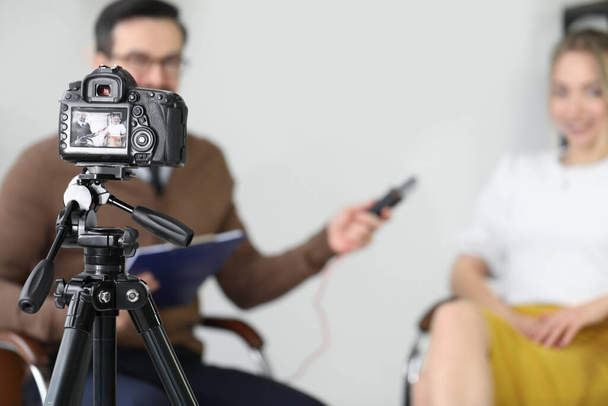 Periodista masculino con micrófono teniendo una entrevista con la mujer en la pantalla de la cámara en el estudio, primer plano - Foto, Imagen