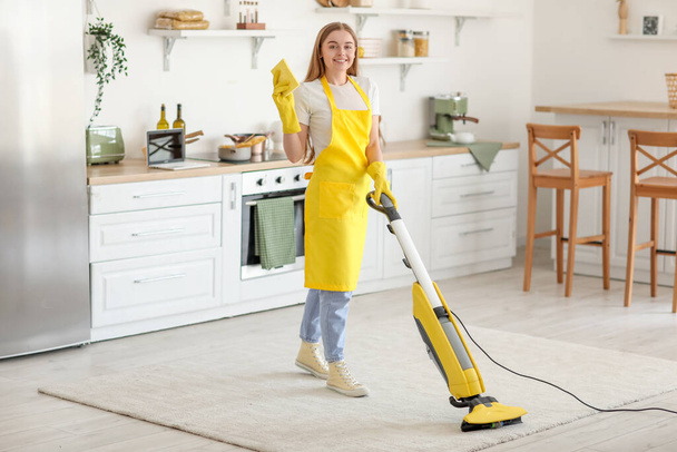 Mladá žena s hadrem vysávání koberec v kuchyni - Fotografie, Obrázek
