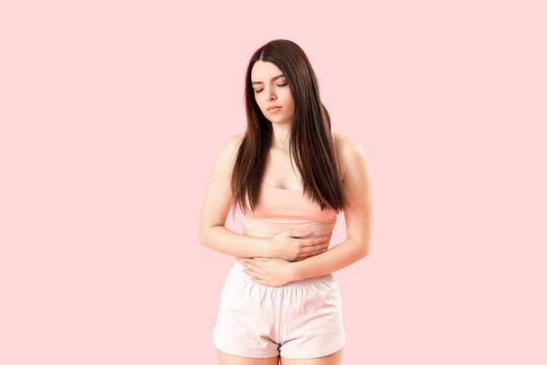 Mladá žena s menstruační křeče na růžovém pozadí - Fotografie, Obrázek